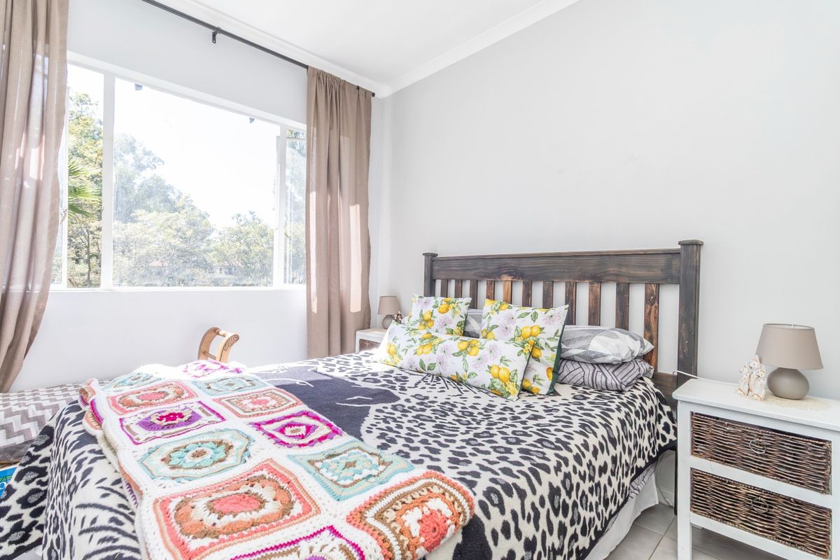 A bright and airy bedroom featuring a large window that allows for ample natural light and a neutral color palette.