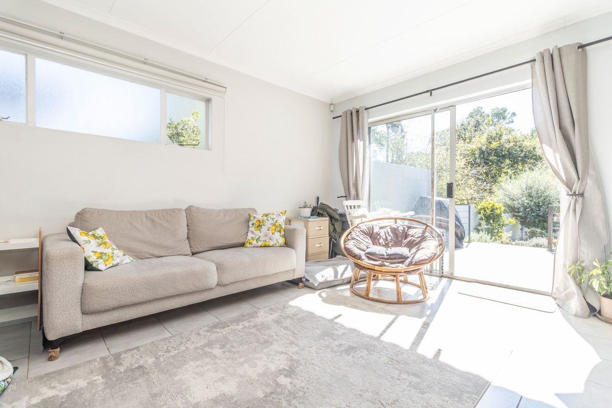 Bright living room featuring tiled flooring and large sliding glass doors that provide direct access to the outdoor patio area.