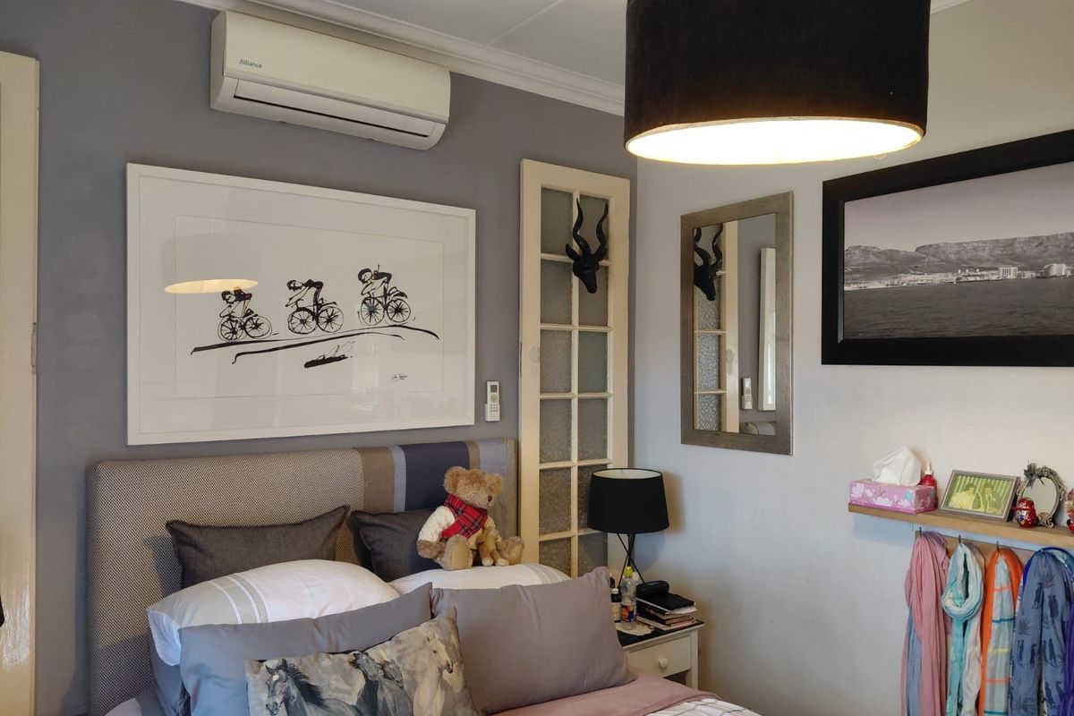 A well-maintained bedroom featuring a wall-mounted air conditioning unit, decorative glass-paneled door, and neutral wall finishes.