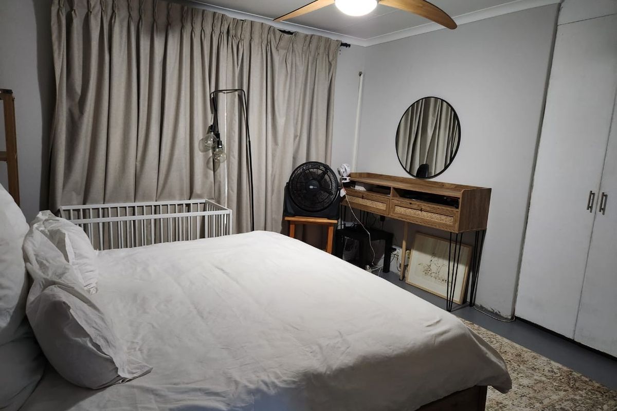 A functional bedroom featuring built-in wardrobes, a ceiling fan, and neutral wall tones, providing a comfortable and practical living space.