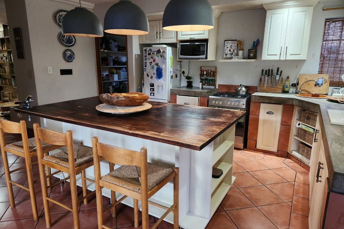 A rustic-style kitchen featuring a large wooden island, built-in cabinetry, a gas stove, and terracotta floor tiles.