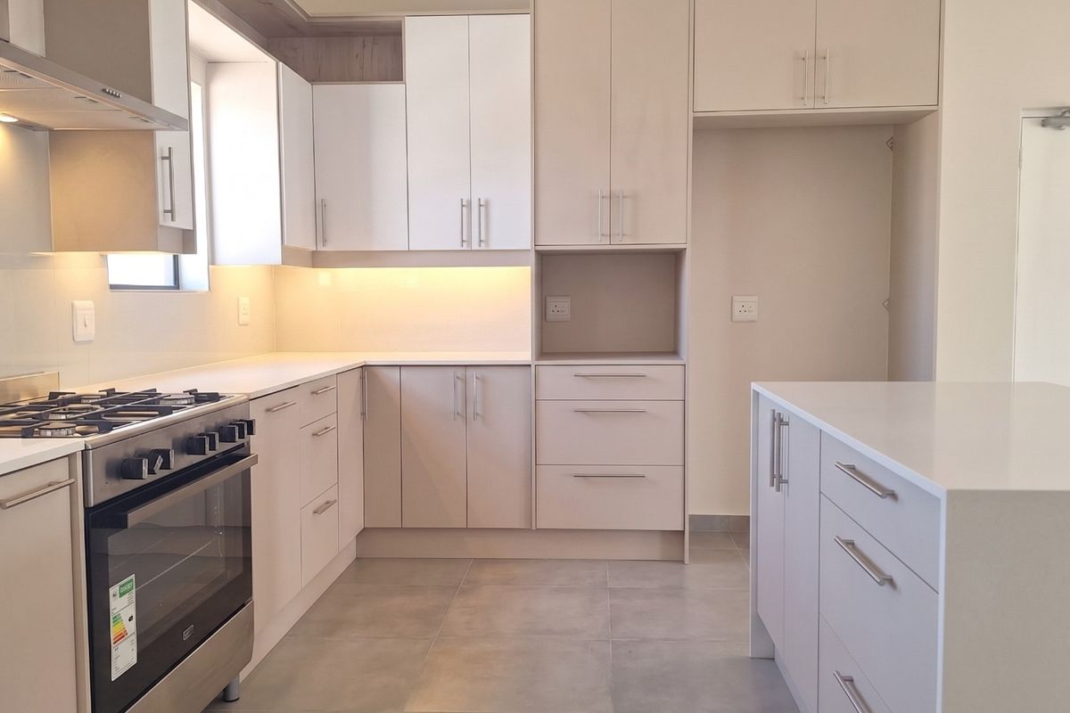 Modern kitchen featuring sleek cabinetry, stone countertops, a gas stove with extractor fan, and a central island with additional storage.
