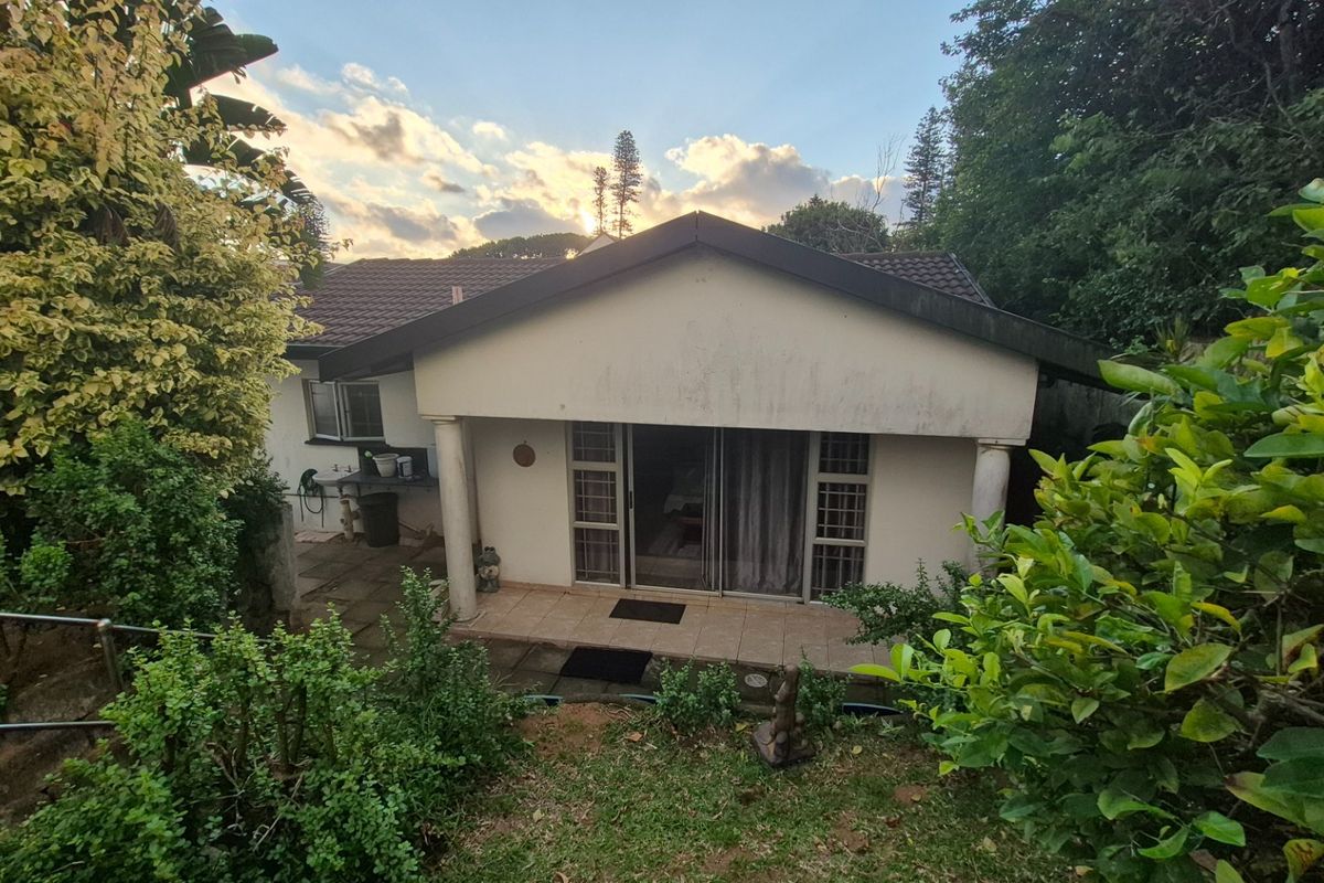 Rear view of the house featuring a covered patio area, tiled flooring, and sliding glass doors leading into the interior.