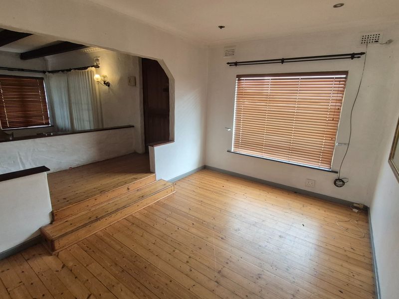 A split-level living area featuring polished timber flooring, recessed lighting, and a raised platform section with exposed timber ceiling beams.