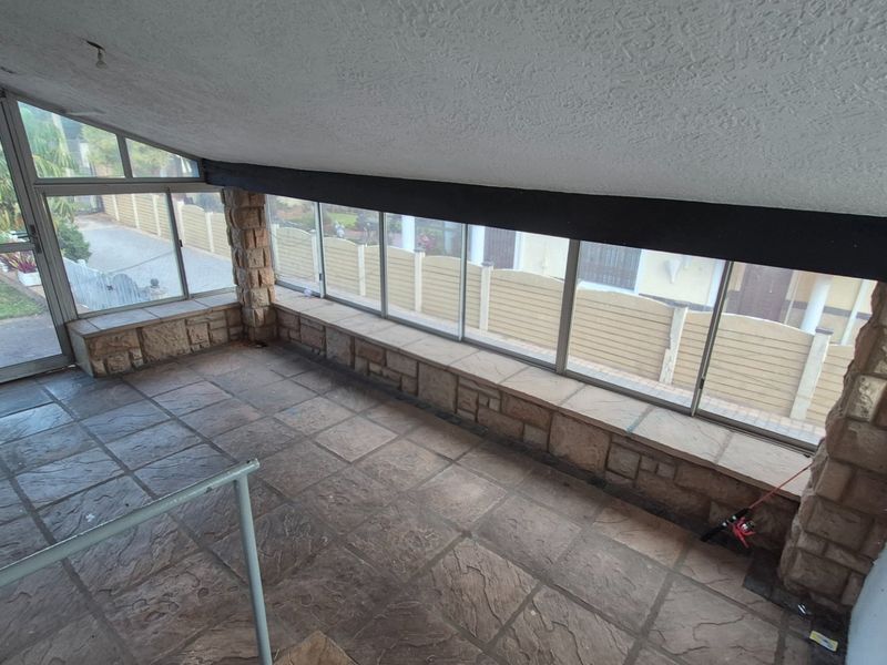 Enclosed sunroom or patio area featuring stone-clad pillars, tiled flooring, and extensive glazing providing views of the surrounding property.
