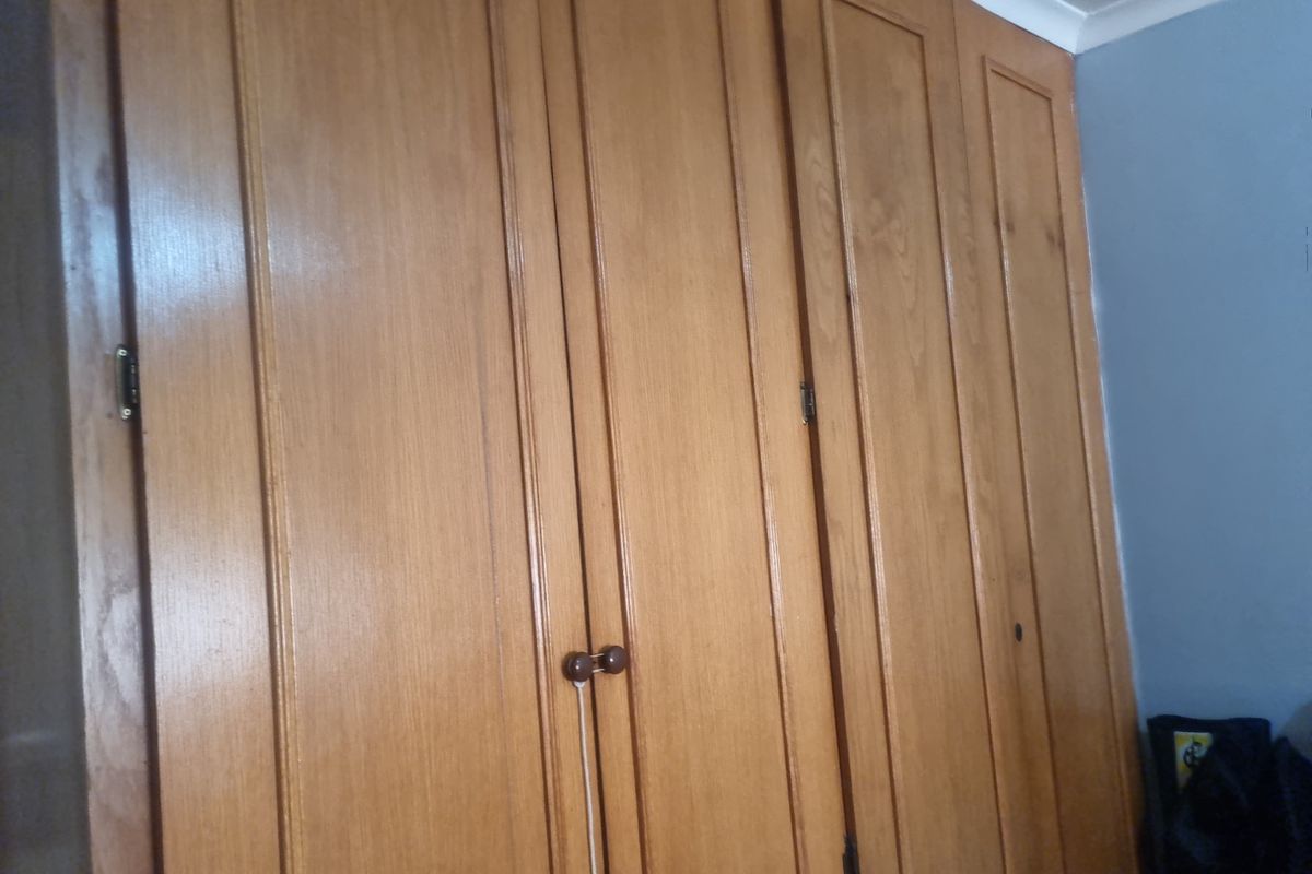 A close-up view of a traditional built-in wooden wardrobe with panelled doors located in a bedroom.
