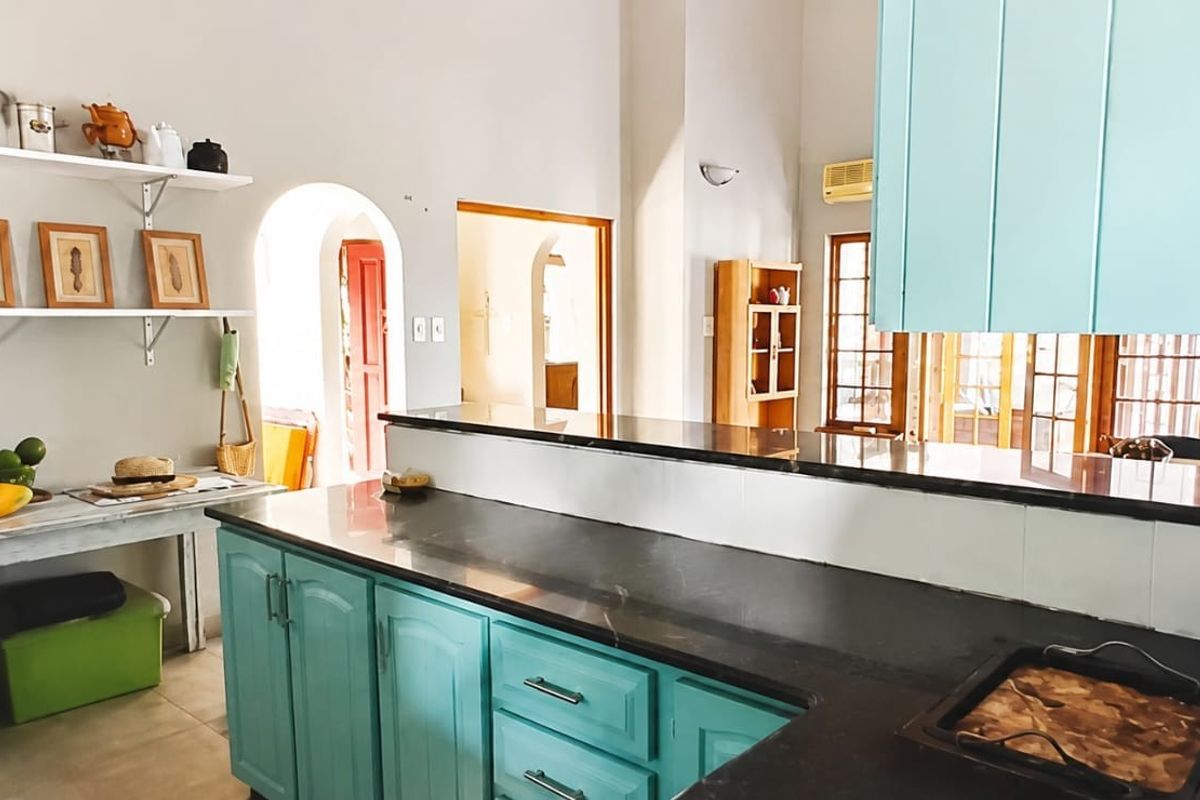 Kitchen featuring teal cabinetry, dark stone countertops, and an open-plan layout with arched doorways leading to adjacent living spaces.