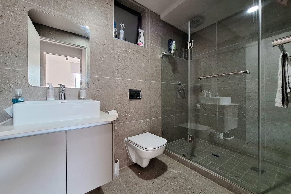 Modern bathroom featuring a wall-mounted vanity, vessel sink, wall-hung toilet, and a spacious walk-in shower with glass enclosure and stone-look tiling.