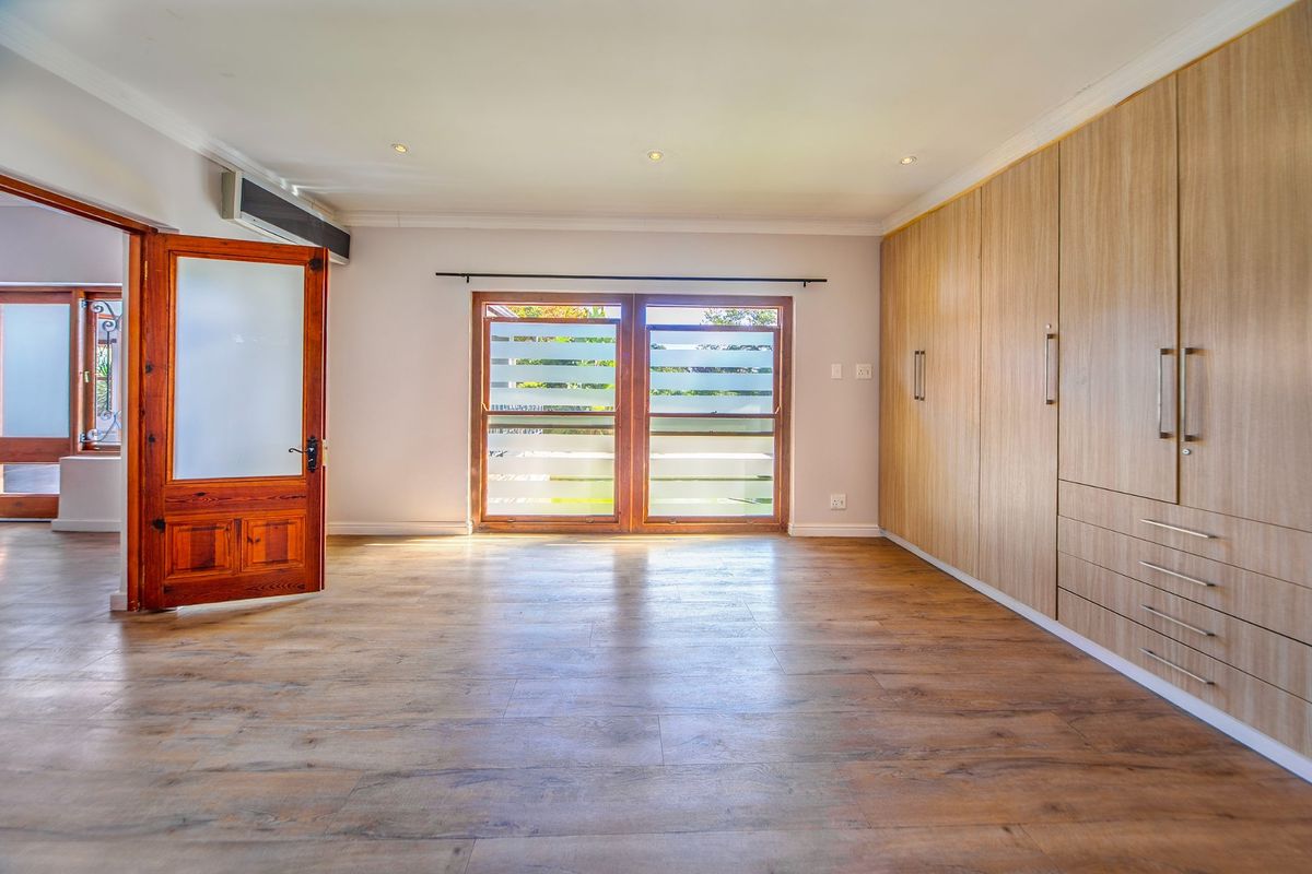 Spacious bedroom featuring wood-look laminate flooring, extensive built-in cabinetry, recessed ceiling lighting, and a split-system air conditioning unit.