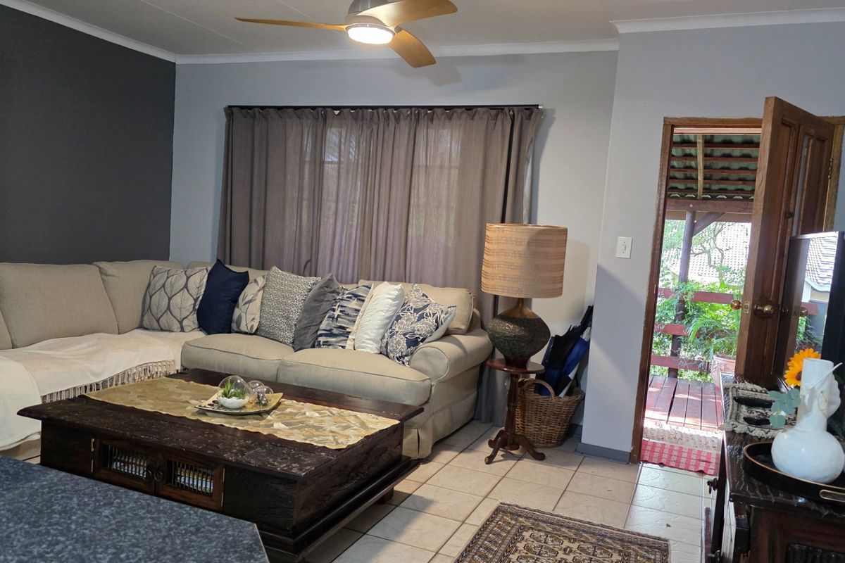 A comfortable living room featuring tiled flooring, a ceiling fan, and direct access to an outdoor patio area.