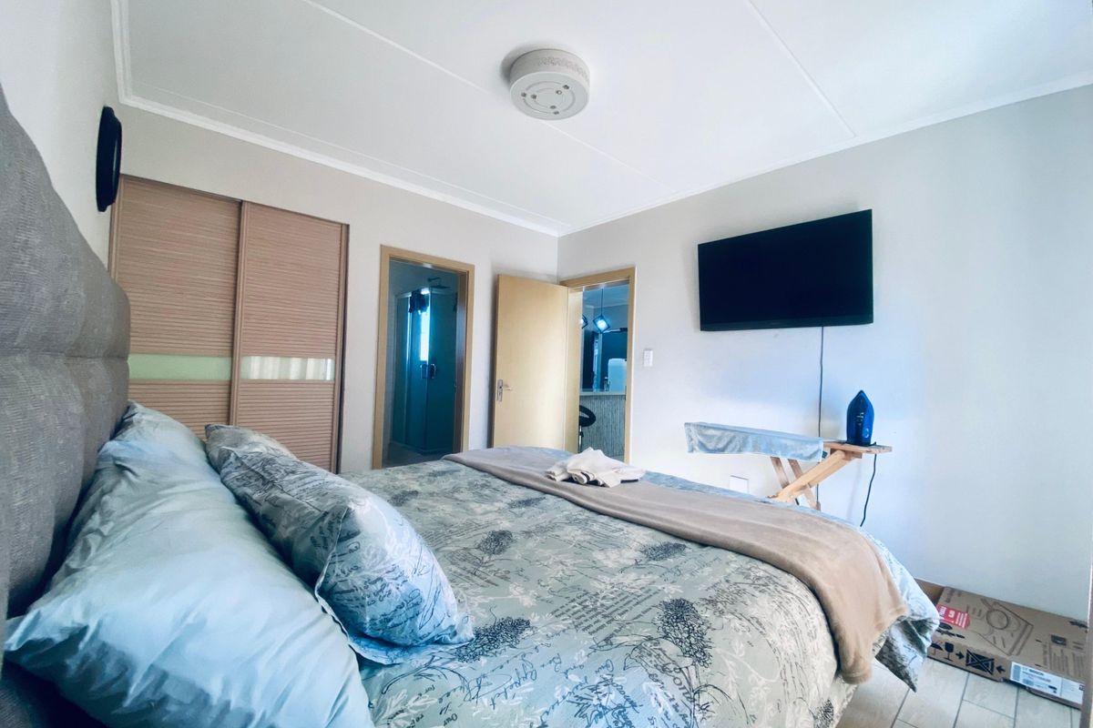 A bedroom featuring built-in sliding door cupboards, tiled flooring, and an en-suite bathroom entrance.