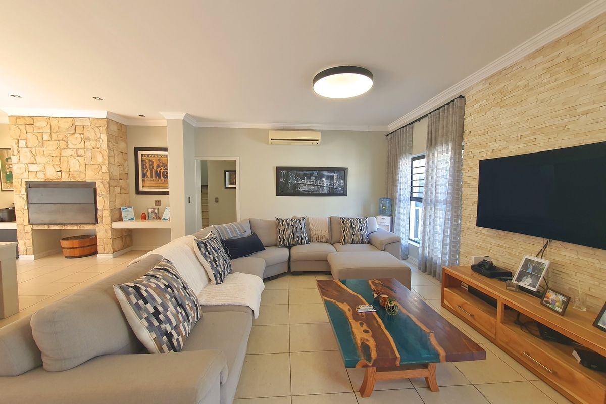 Spacious living room featuring a stone accent wall with a built-in fireplace, tiled flooring, and a split-system air conditioner.