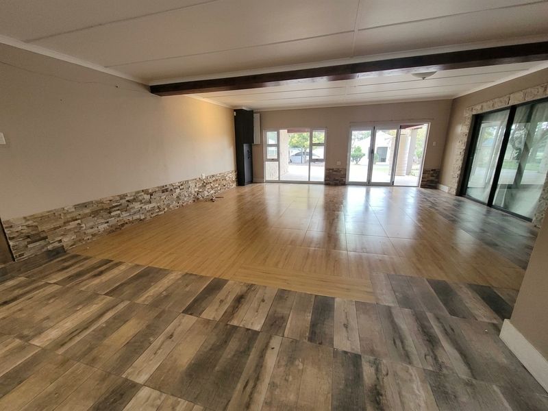 Spacious open-plan living area featuring wood-look tile flooring, stone-clad wall accents, and large sliding glass doors providing access to the outdoor patio.