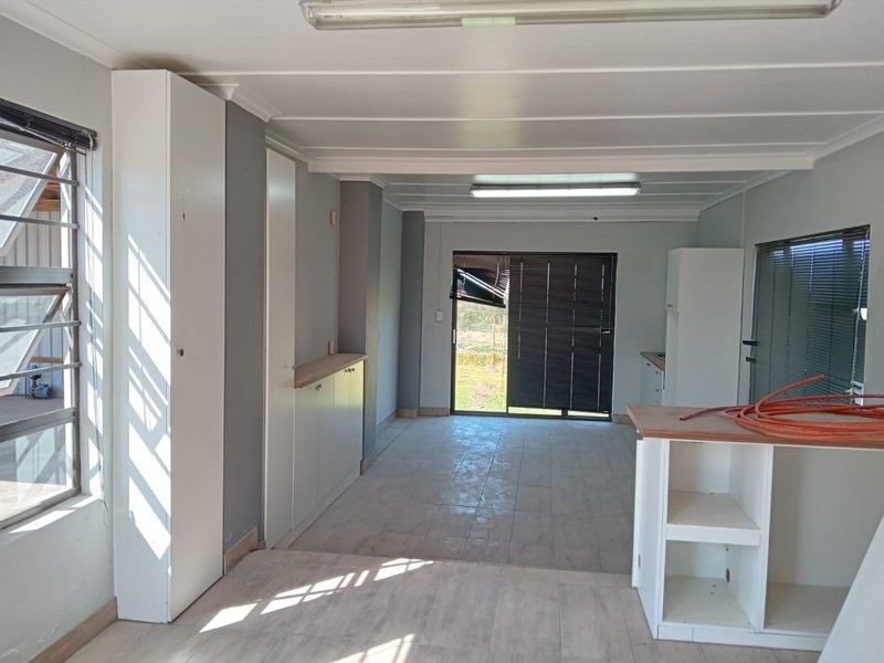 An open-plan living and kitchen area featuring built-in cabinetry, tiled flooring, and sliding glass doors leading to the exterior.