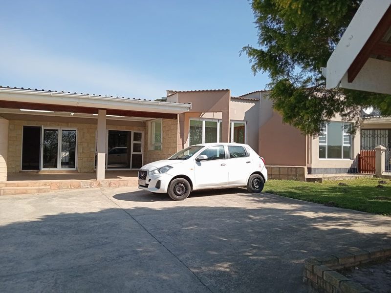 Front exterior view of the farm property featuring a covered patio area, stone cladding accents, and a concrete driveway.