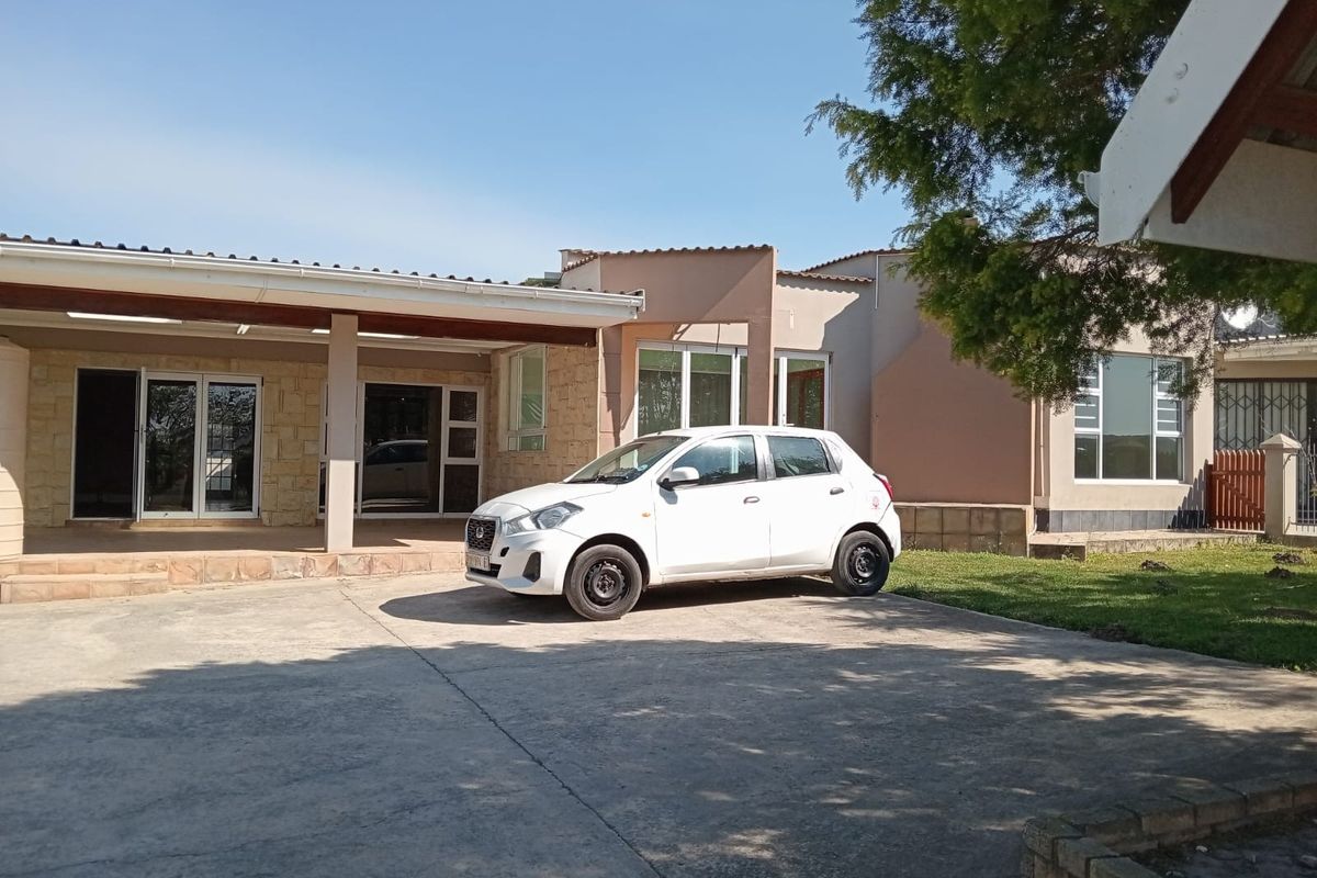Front exterior view of the farm property featuring a covered patio area, stone cladding accents, and a concrete driveway.