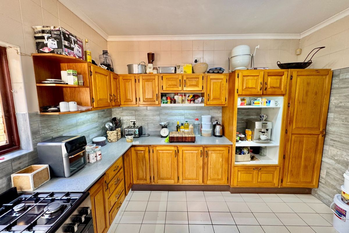 A functional kitchen featuring traditional timber cabinetry, tiled splashbacks, and a gas stove, offering a classic layout with ample storage space.