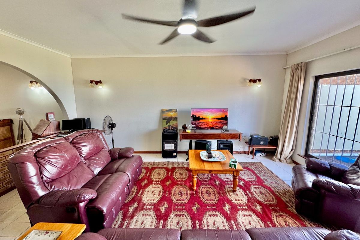 A spacious living room featuring tiled flooring, a ceiling fan, and large sliding glass doors providing access to the exterior.