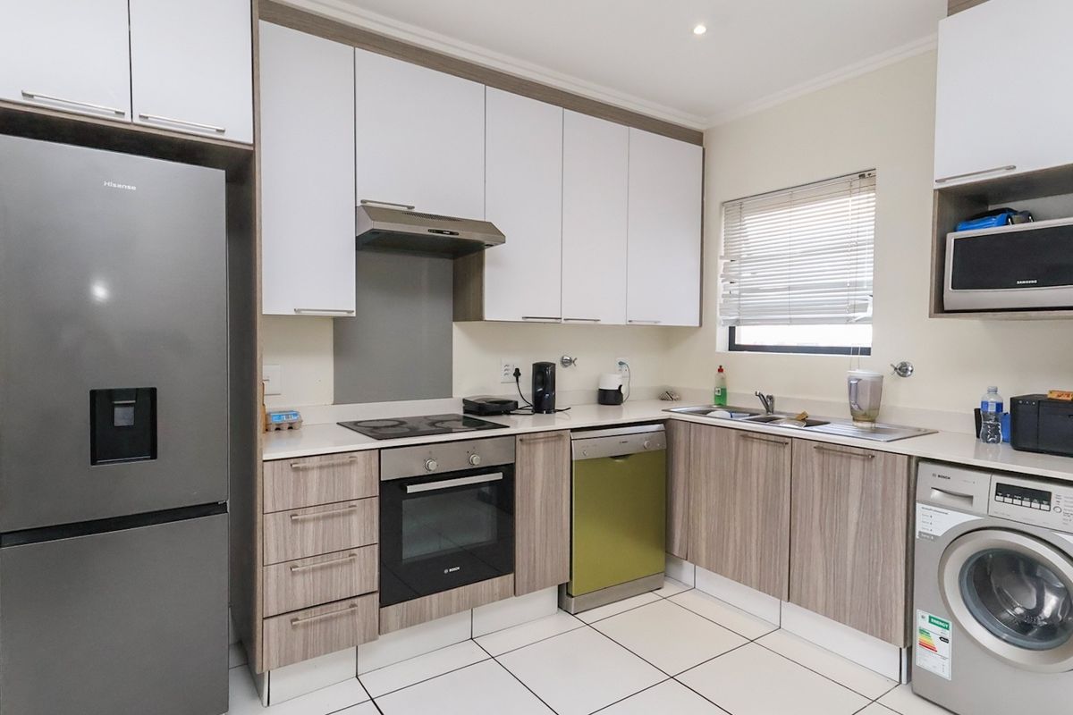 Modern kitchen featuring two-tone cabinetry, integrated appliances, electric hob, oven, extractor fan, and tiled flooring with ample storage space.
