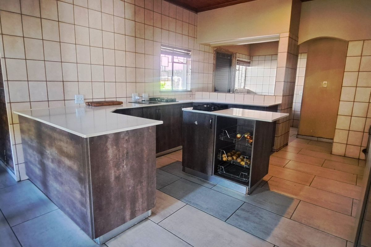 A functional kitchen featuring a central island, built-in cabinetry, tiled splashbacks, and tiled flooring, offering a practical layout for meal preparation.