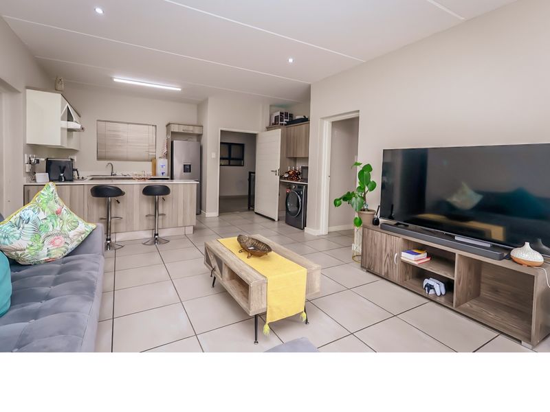 Open-plan living area featuring a modern kitchen with island, tiled flooring, and a dedicated laundry nook, creating a functional and cohesive living space.