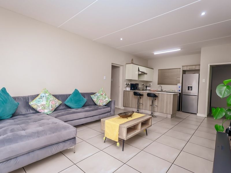 An open-plan living area featuring a modern kitchen with built-in cabinetry, a breakfast island, and neutral tiled flooring throughout the space.