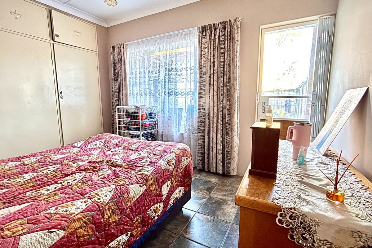 A bedroom featuring built-in cupboards, tiled flooring, and direct access to an outdoor area through a glass door.