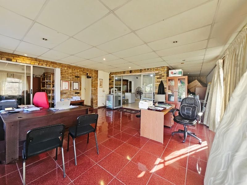 Spacious office area featuring exposed brick walls, red tiled flooring, and a suspended ceiling with integrated lighting.