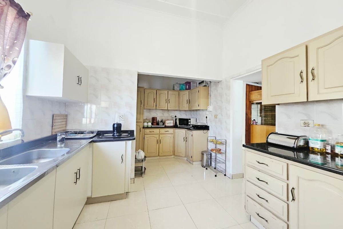 A functional kitchen featuring ample built-in cabinetry, granite countertops, a double basin sink, and tiled finishes throughout.