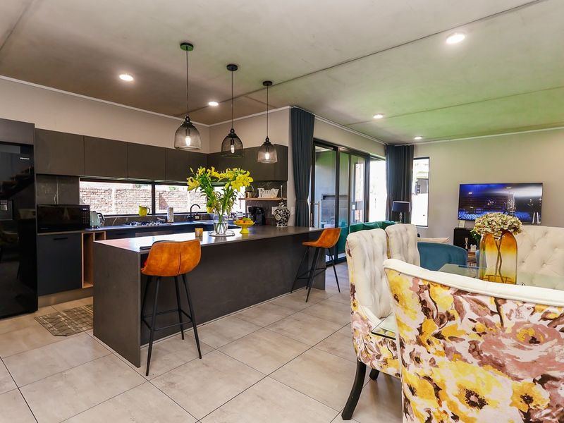 Modern open-plan living area featuring a sleek kitchen with a large island, contemporary cabinetry, and seamless flow to the dining and lounge spaces.