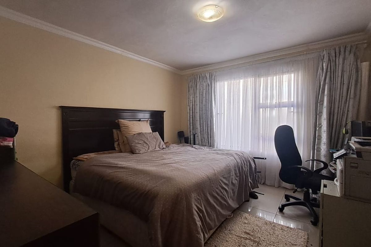 A standard bedroom featuring tiled flooring, crown molding, and large windows with curtain tracks, providing a functional living space.