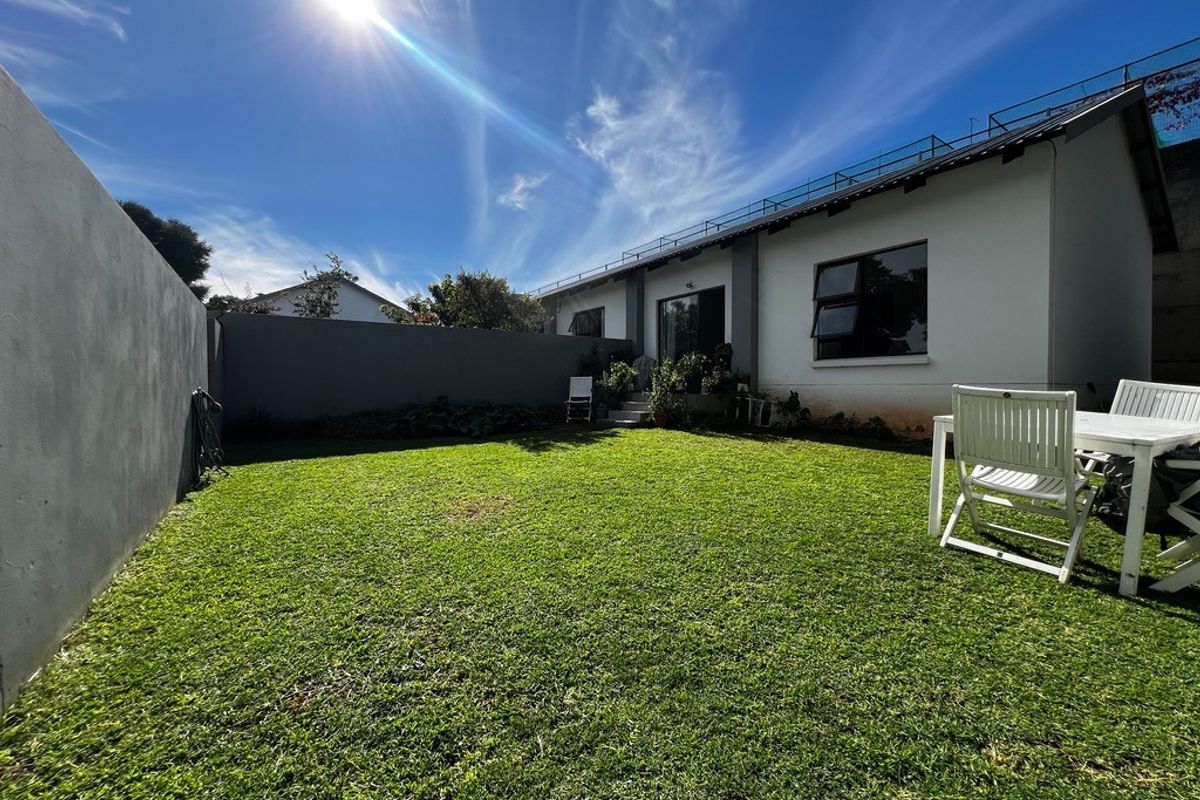 A private rear garden featuring a well-maintained lawn, perimeter boundary walls, and direct access to the main dwelling.