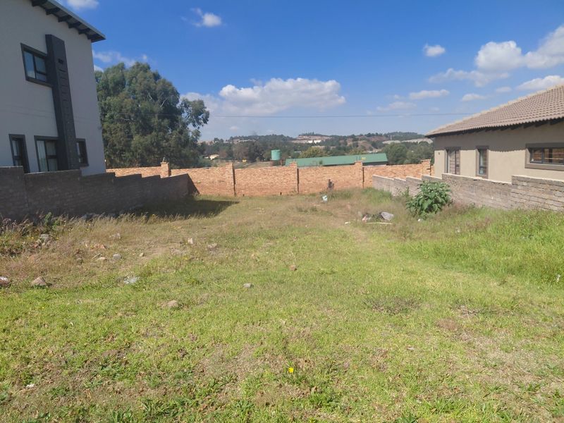 A vacant residential plot featuring perimeter brick boundary walls and established neighboring properties, offering a clear space for future development.