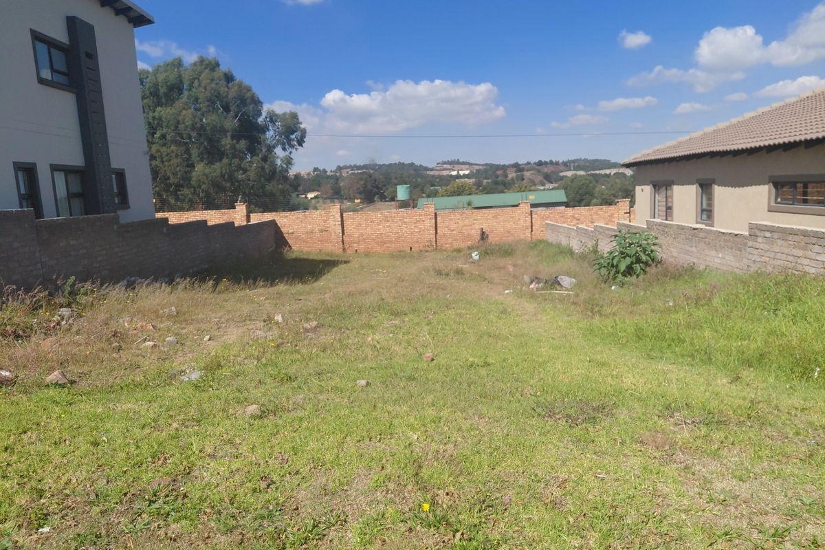 A vacant residential plot featuring perimeter brick boundary walls and established neighboring properties, offering a clear space for future development.