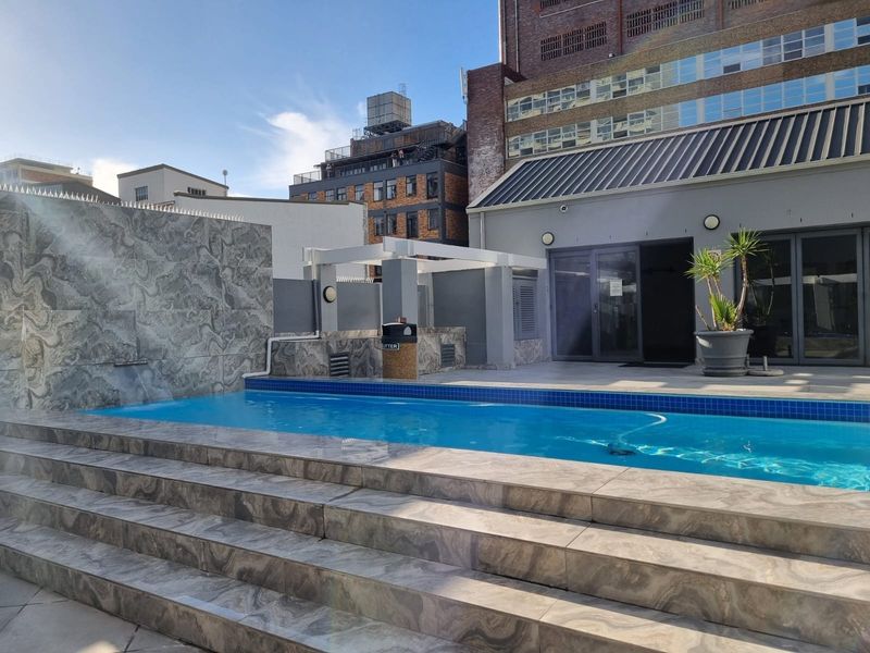 A well-maintained outdoor pool area featuring tiled steps, a water feature, and a paved deck, providing a modern recreational space.
