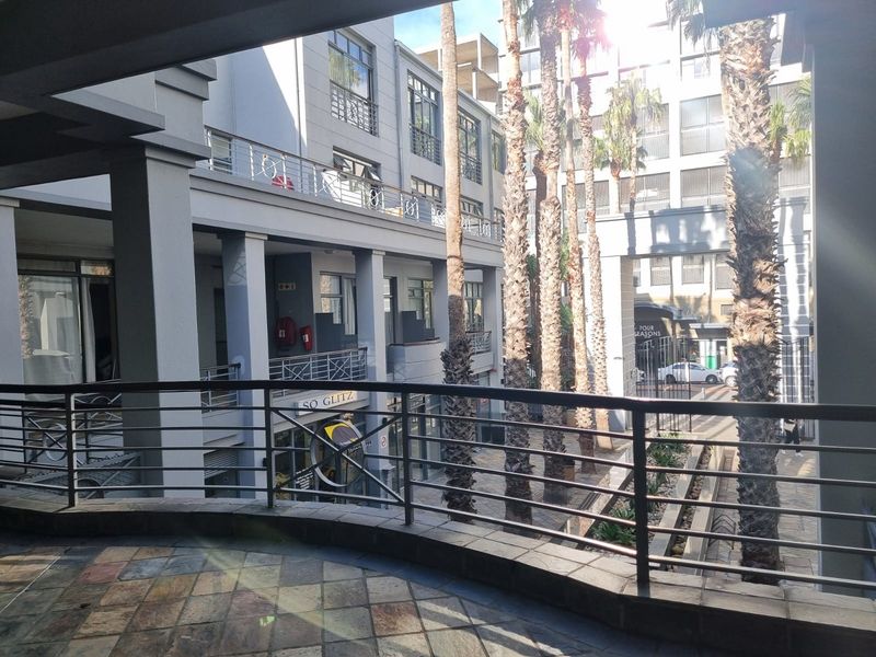 A view from a balcony overlooking a landscaped courtyard with palm trees and surrounding apartment building facades.