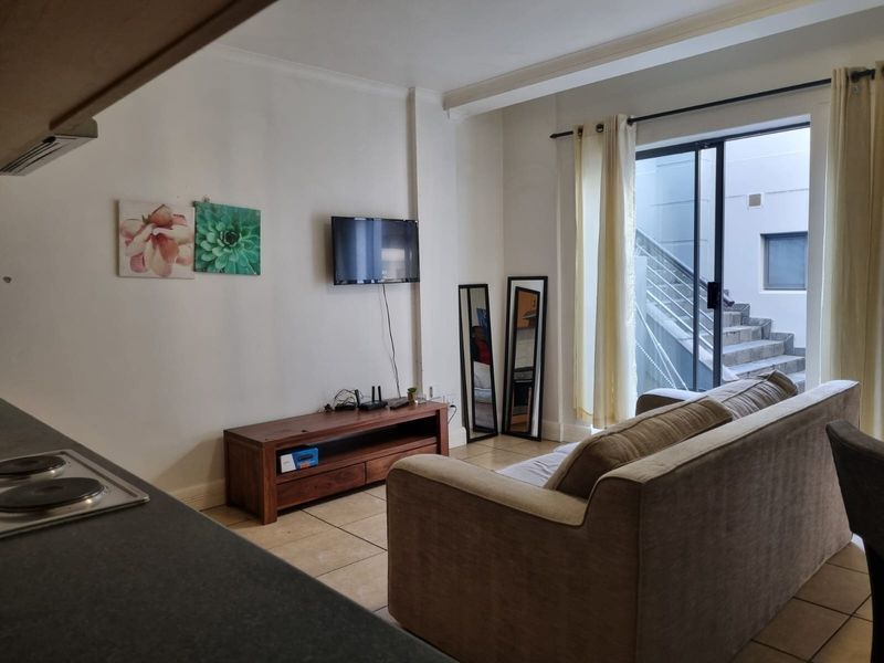 Open plan living area featuring tiled flooring and a sliding glass door providing access to an external staircase.