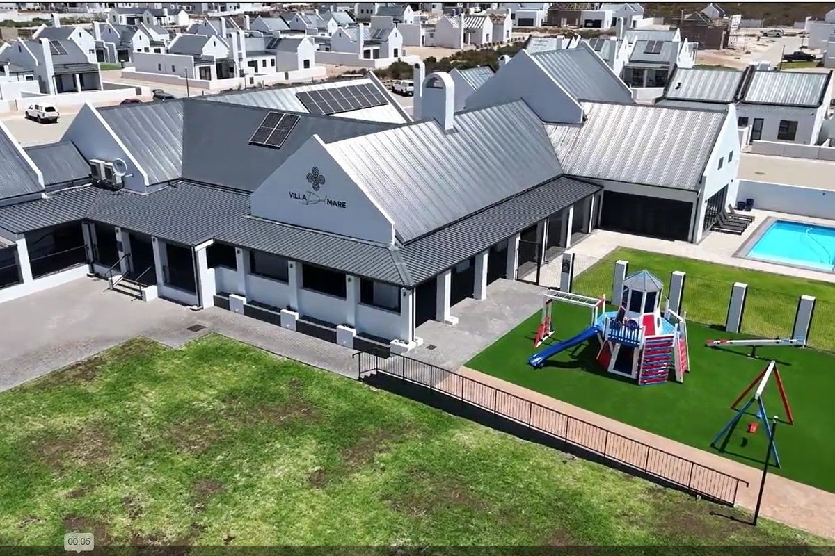 Aerial view of a residential property featuring a metal roof with solar panels, a swimming pool, and a landscaped garden area.