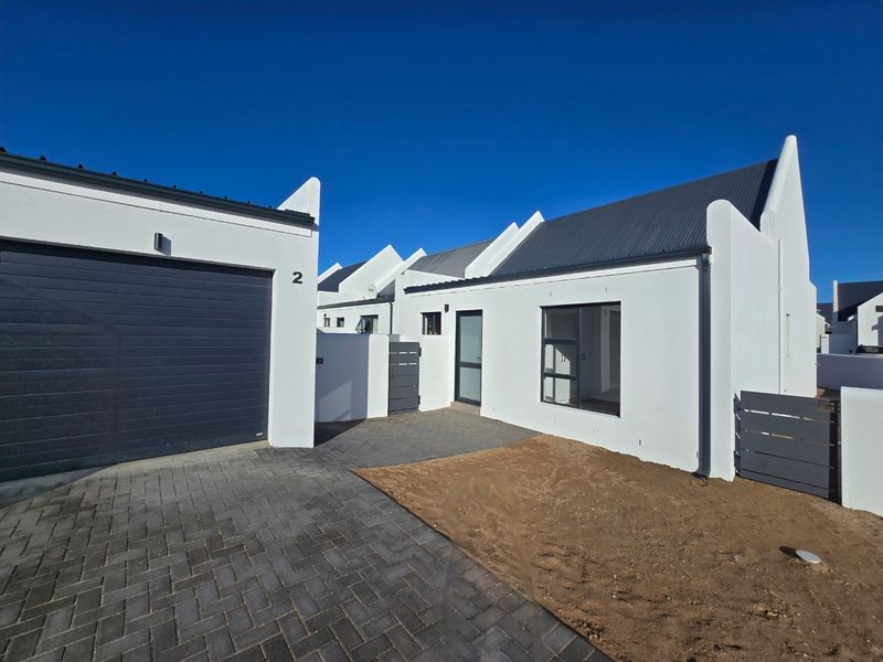 Modern single-story home exterior featuring a paved driveway, attached garage, and clean white facade with contemporary gabled roof lines.
