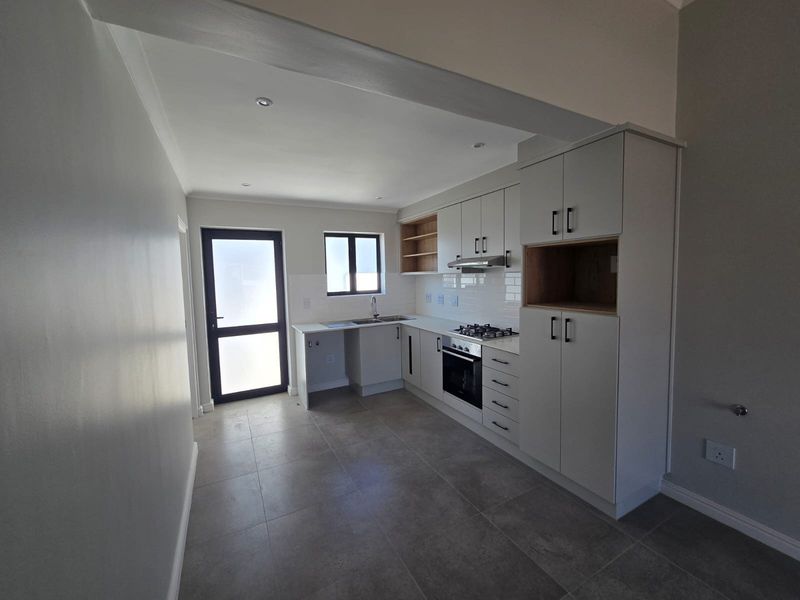 Modern kitchen featuring light grey cabinetry, gas hob, under-counter oven, subway tile backsplash, and tiled flooring with direct access to the exterior.