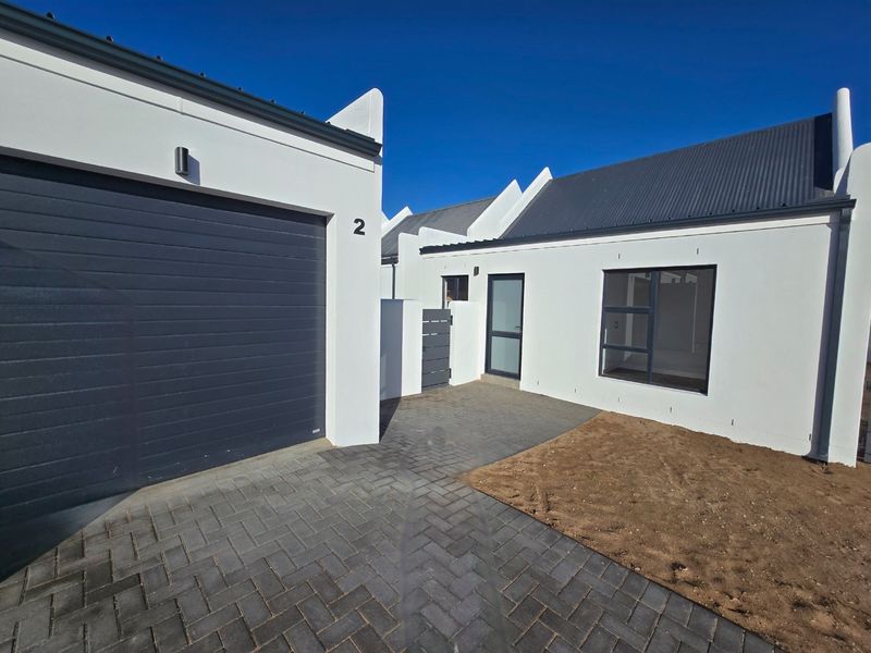 Front exterior view of a modern home featuring a paved driveway, garage, and clean white facade with dark metal roofing.