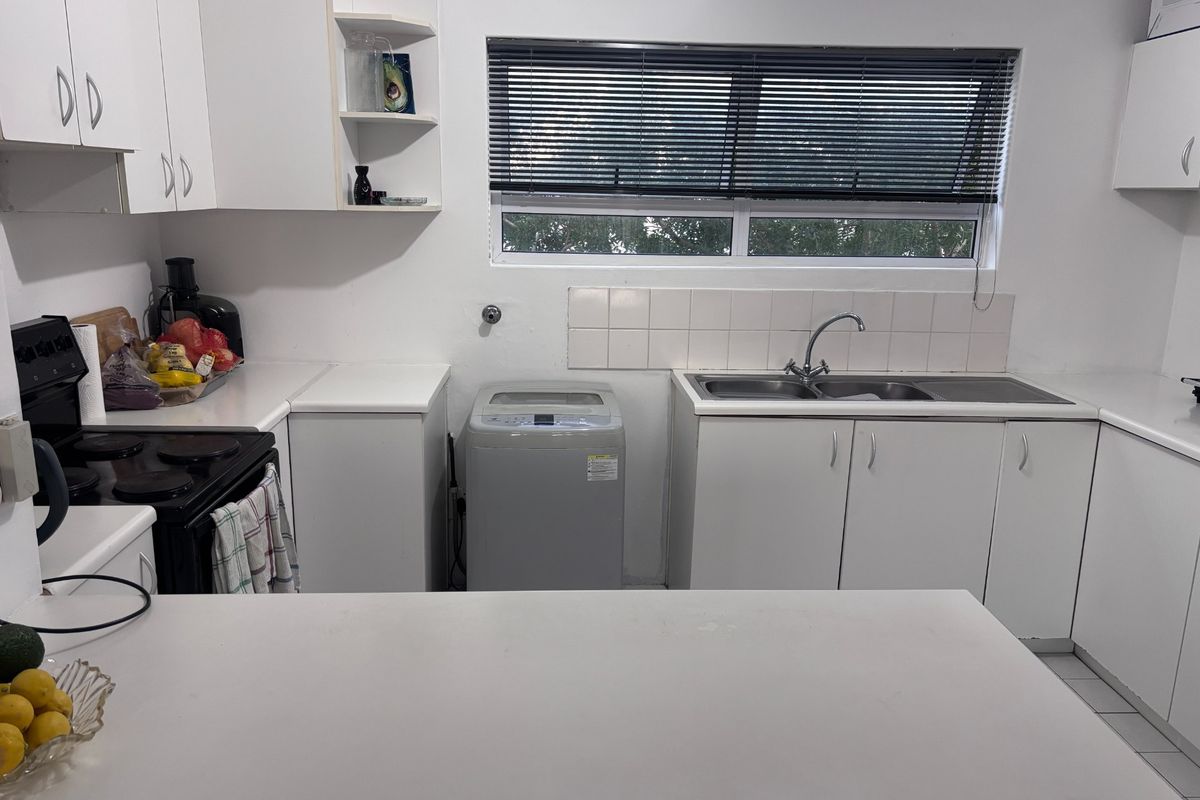 Functional kitchen featuring white cabinetry, a double basin sink, tiled splashback, and space for a washing machine.