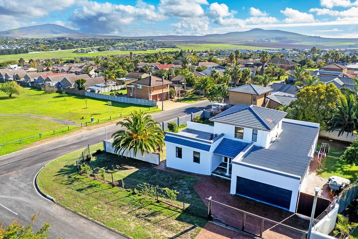Aerial view of a modern residential property featuring a tiled roof, double garage, and landscaped garden in a suburban neighborhood setting.