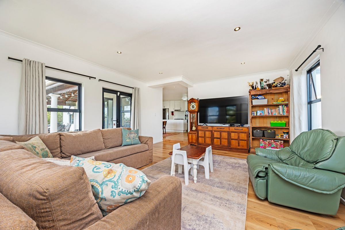 Spacious open-plan living area featuring hardwood flooring, recessed lighting, and direct access to an outdoor patio through glass doors.