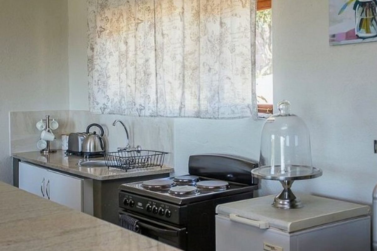 A compact kitchen area featuring a built-in sink, stone-look countertops, and a freestanding electric stove.