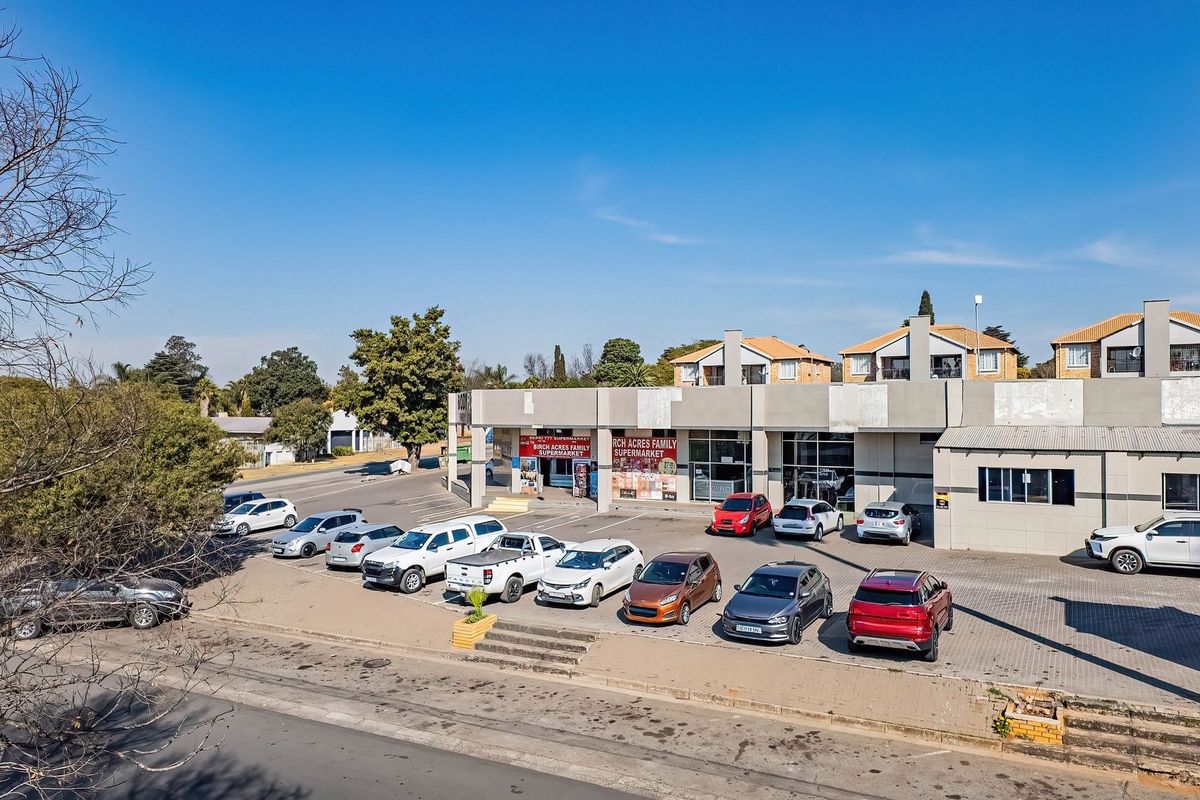 Aerial view of a commercial property featuring a paved parking lot and building frontage with established retail signage.