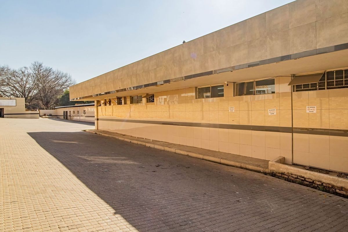 A view of the rear exterior of the commercial property, featuring a paved driveway and a tiled building facade.