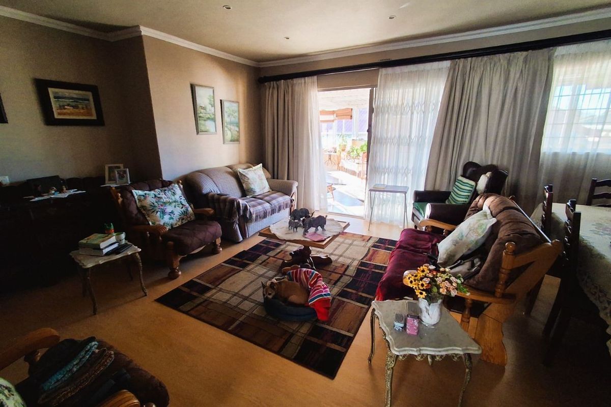 Spacious living room featuring laminate flooring, recessed ceiling lighting, and large sliding glass doors providing direct access to an outdoor patio area.