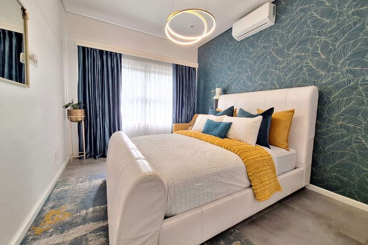 A well-maintained bedroom featuring tiled flooring, a split-system air conditioner, recessed lighting, and a decorative feature wall.