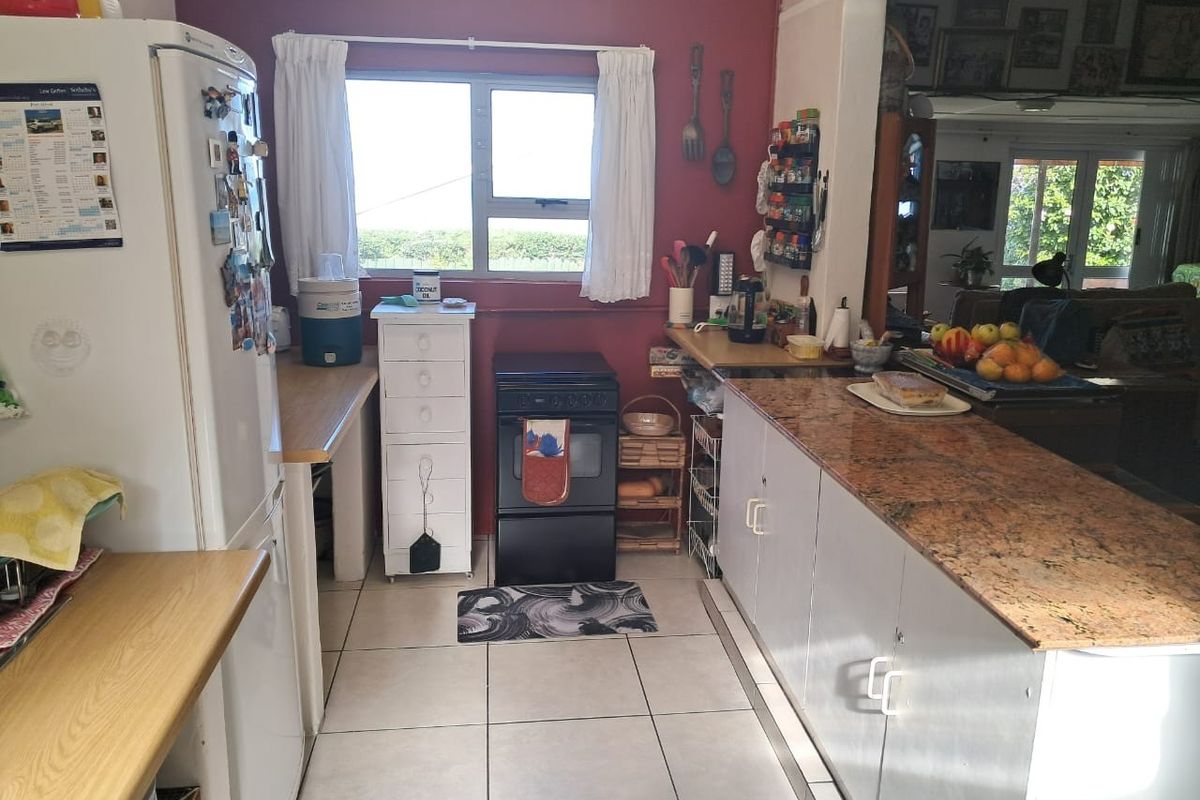 A functional kitchen featuring granite countertops, tiled flooring, and a freestanding oven, offering a practical layout with potential for modern cosmetic updates.